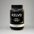 Black protein powder container with RZLVD branding on a gray background